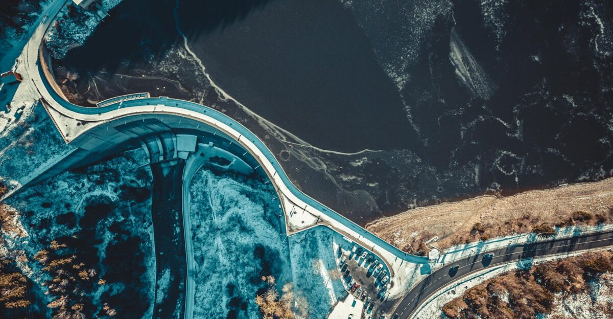 Drone shot of a dam with icy river and snowy landscape showcasing winter architecture