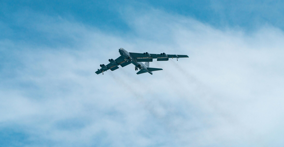 A B-52 Stratofortress aircraft soars through a clear blue sky on a sunny day.