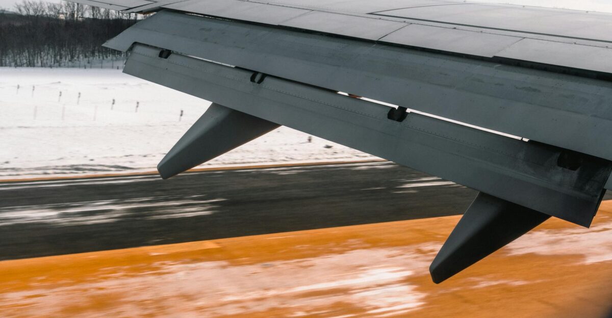 Close-up of an airplane wing during landing on a snowy runway showcasing aviation dynamics