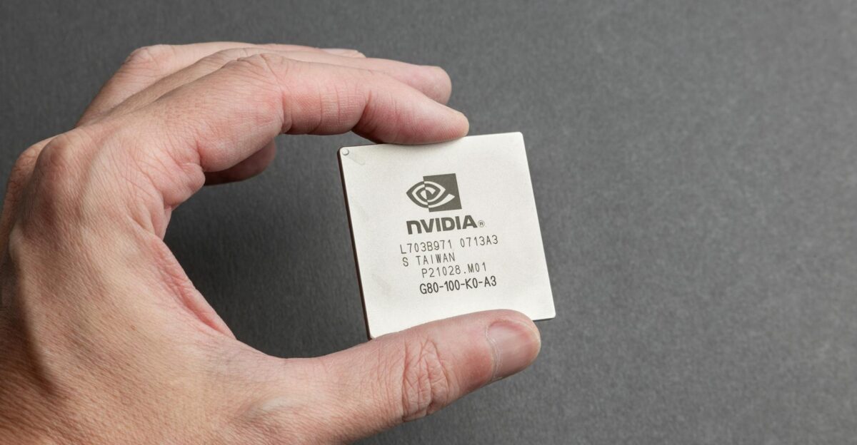 A close-up view of a person holding an Nvidia chip with a gray background