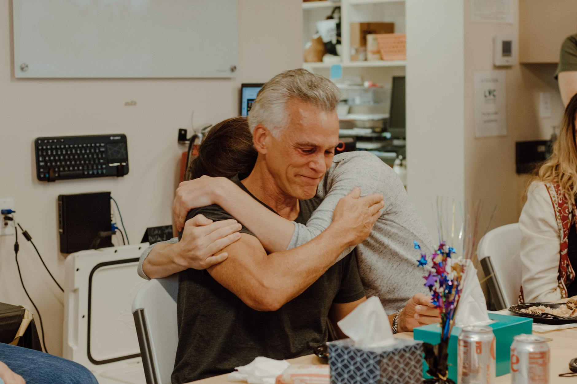 Emotional embrace among colleagues during a heartfelt gathering in an office setting