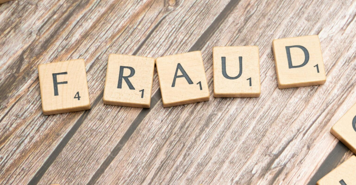 Alphabet tiles arranged to spell 'fraud' on a wooden surface, symbolizing deception.