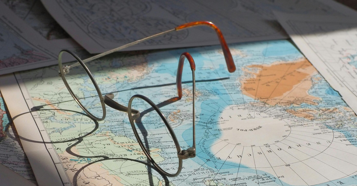 Classic eyeglasses casting artistic shadows on vintage world maps in sunlight.