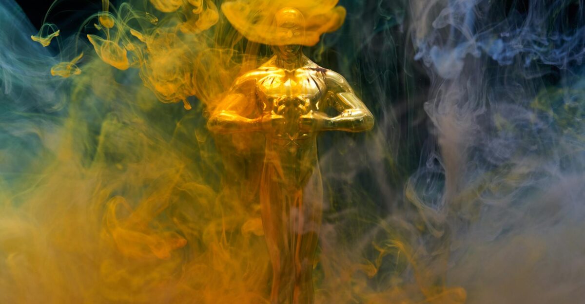 A golden statuette enveloped in vibrant yellow and blue smoke symbolizing achievement and success