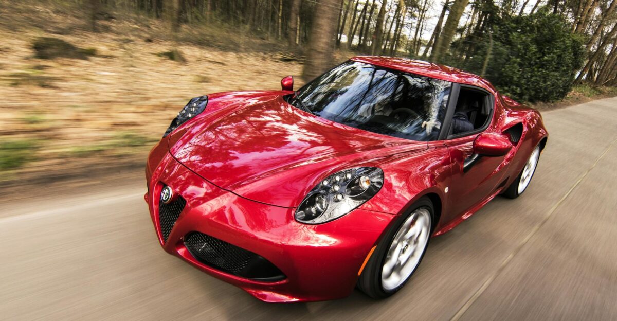A sleek red sports car driving fast on a forest road showcasing speed and luxury