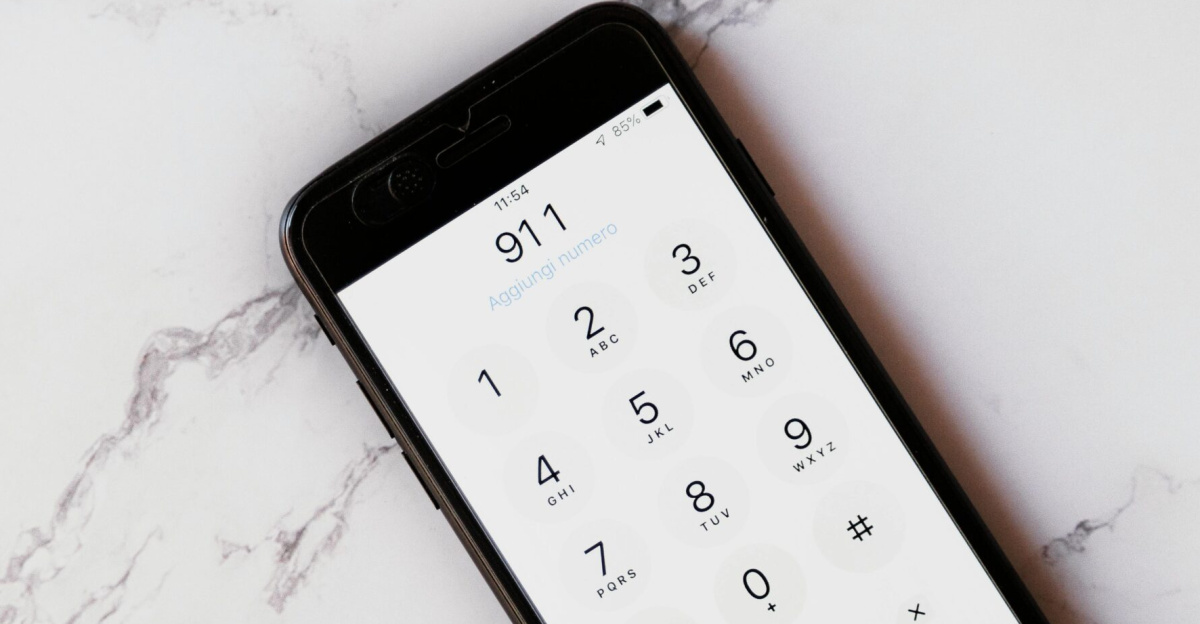 Close-up of a smartphone displaying the emergency number 911 on a white marble surface.