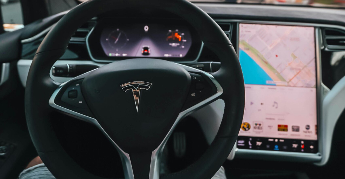 Interior view of a Tesla Model X steering through palm-lined streets of Santa Monica at twilight.