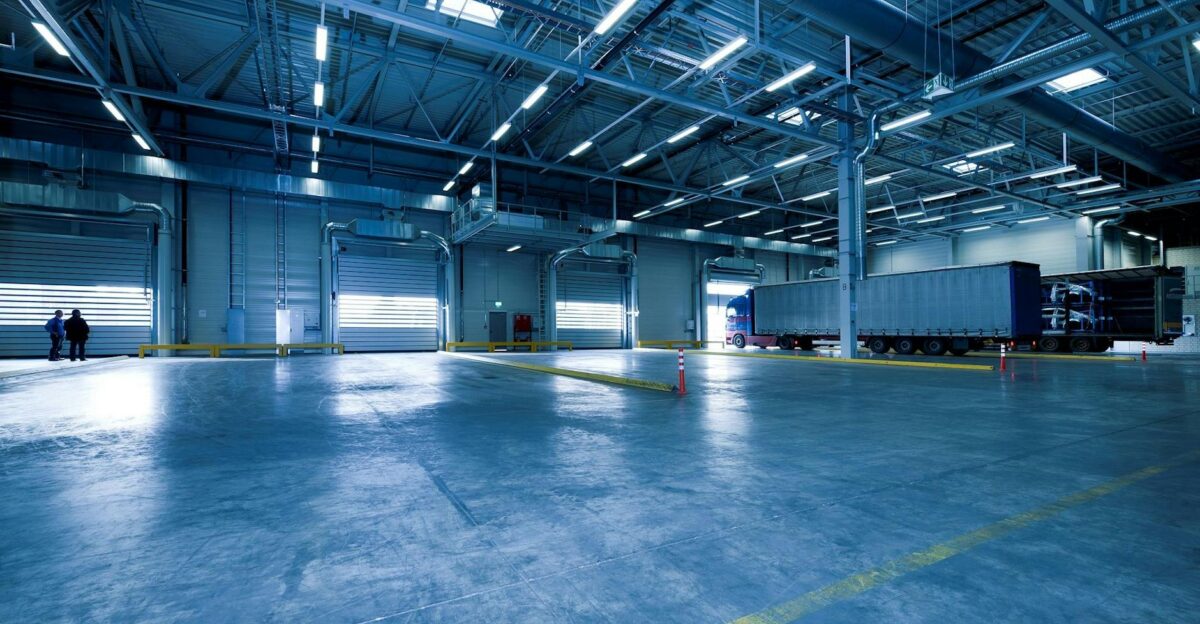 Wide view of an empty modern warehouse with industrial lighting and trucks
