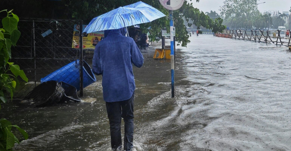 Street scene in Kolkata during monsoon flooding with pedestrian and cars.