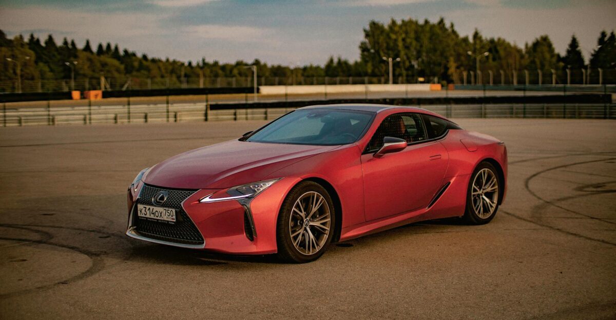 Red Lexus sports car parked on an empty race track under clear skies