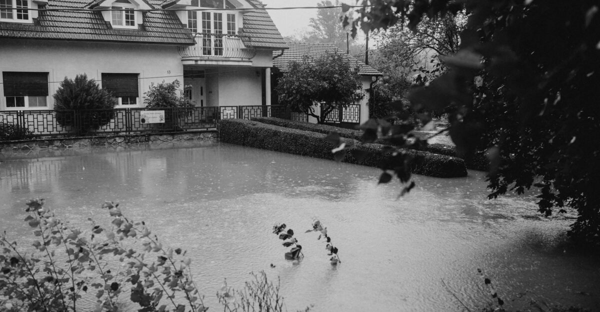 Black and white image of a suburban house affected by flooding during heavy rain