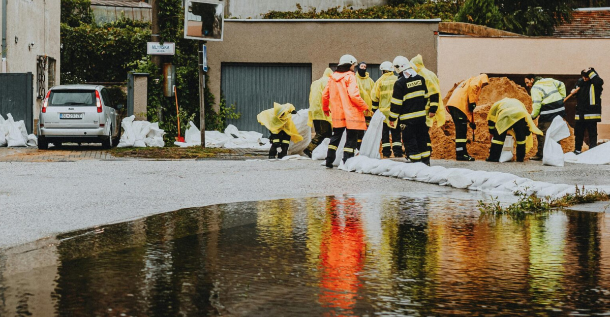 Emergency responders in reflective gear addressing floodwaters on a residential street.