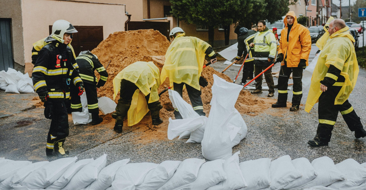 Emergency response team filling sandbags on a rainy street to prevent flooding.