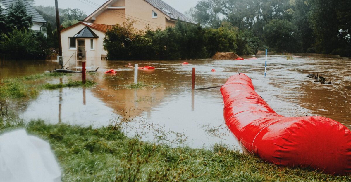 Flooded residential area protected by red flood barriers showing severe weather impact
