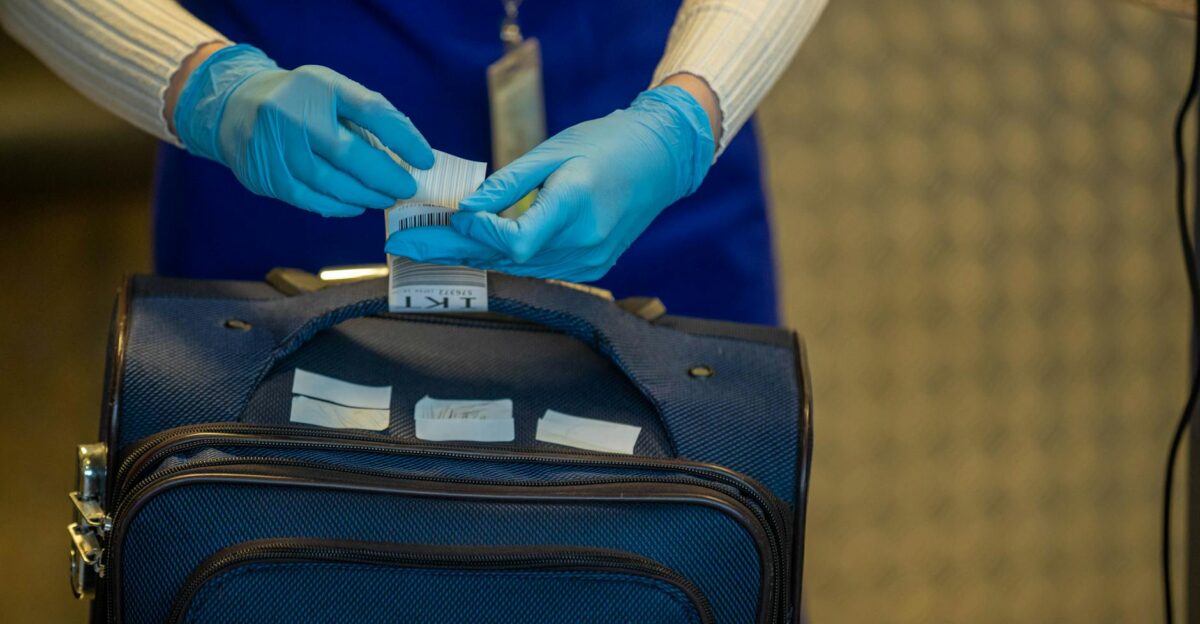Close-up of airport security process with gloved hands inspecting luggage tags