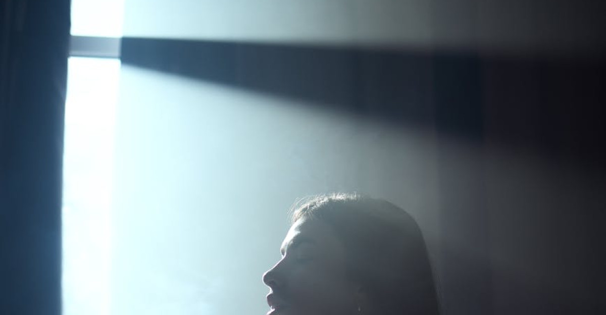 Silhouette of a woman holding peonies with dramatic lighting from window