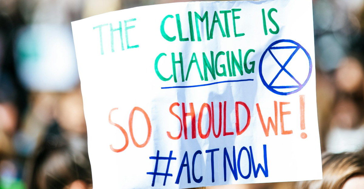 Crowd gathering for climate change protest, holding activist sign.