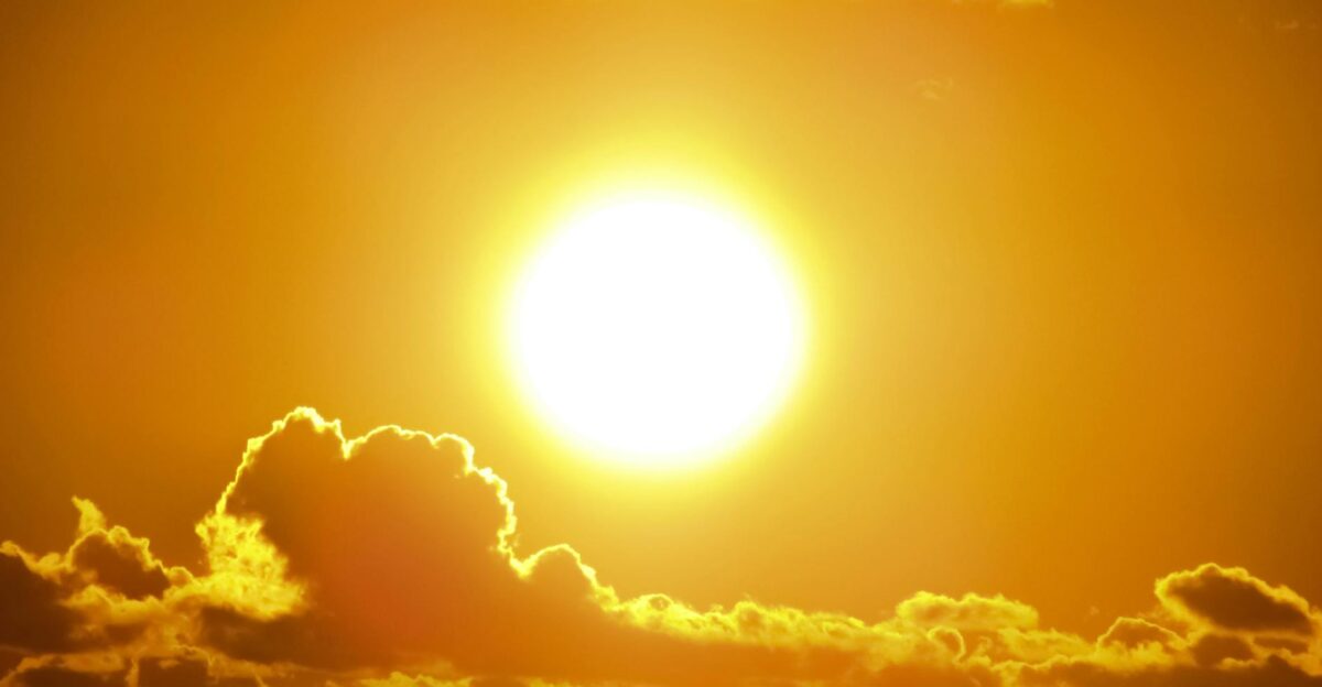 A stunning view of the golden sun shining through clouds at sunset casting a warm glow