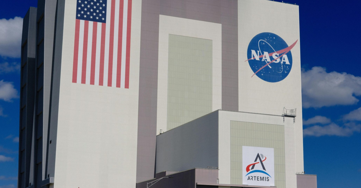 The iconic NASA Vehicle Assembly Building at Kennedy Space Center in bright daylight.