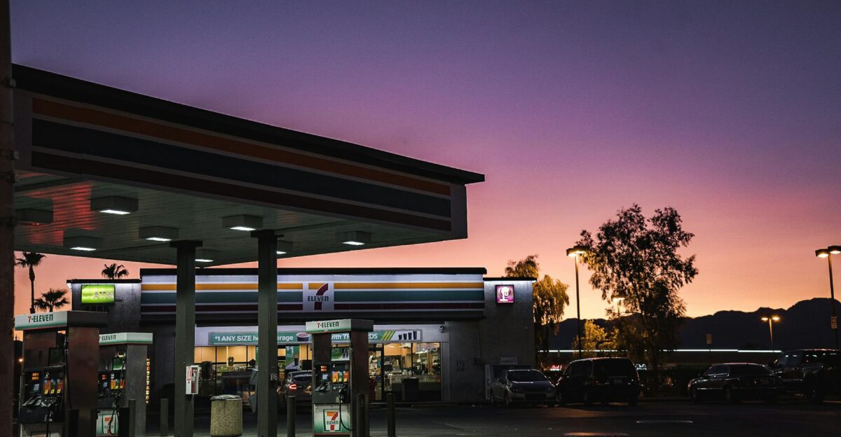 A gas station at dusk with a vibrant sunset background in an urban area
