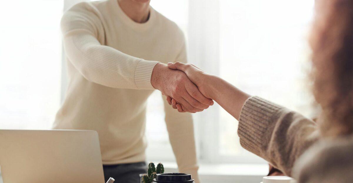 Close-up of professionals shaking hands over coffee in a modern office