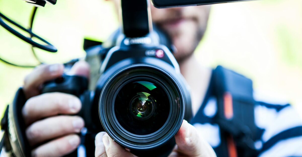 A close-up shot of a cameraman filming focusing on the camera lens and equipment