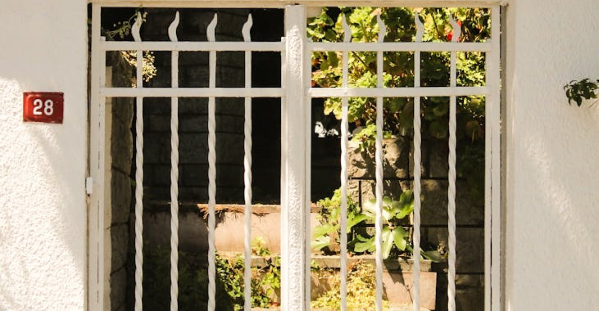 White wrought iron gate adorned with plants under sunlight giving an inviting atmosphere