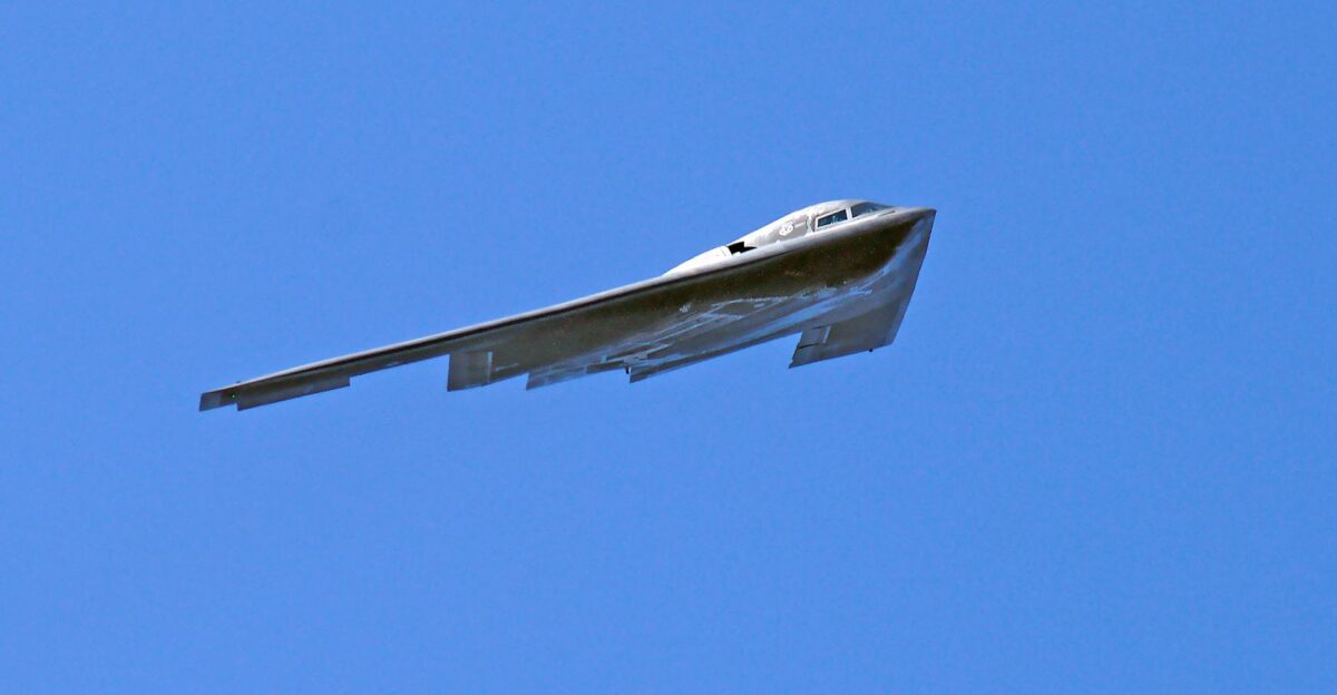 A B-2 Spirit stealth bomber flying in clear blue skies showcasing its advanced aerodynamics