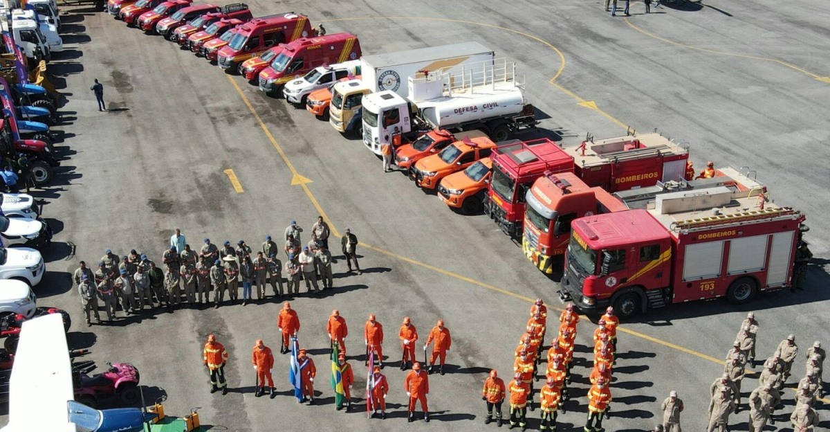 Aerial shot of fire trucks, emergency vehicles, and personnel in a training exercise. Clear day overview.