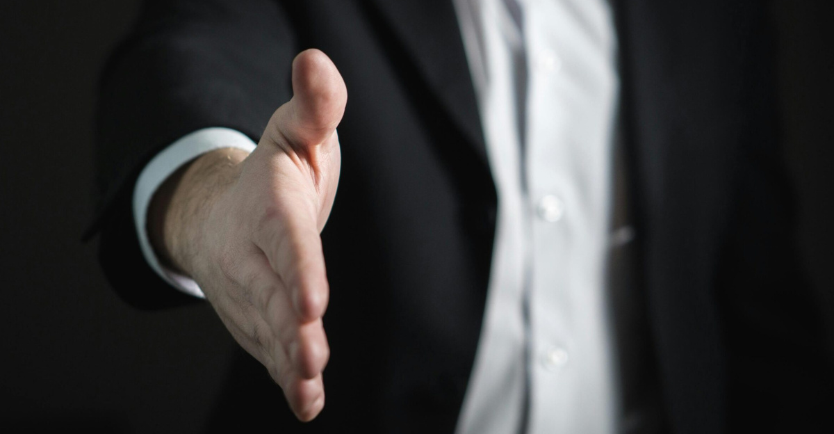 Close-up of a businessman extending hand for a handshake, symbolizing agreement and partnership.