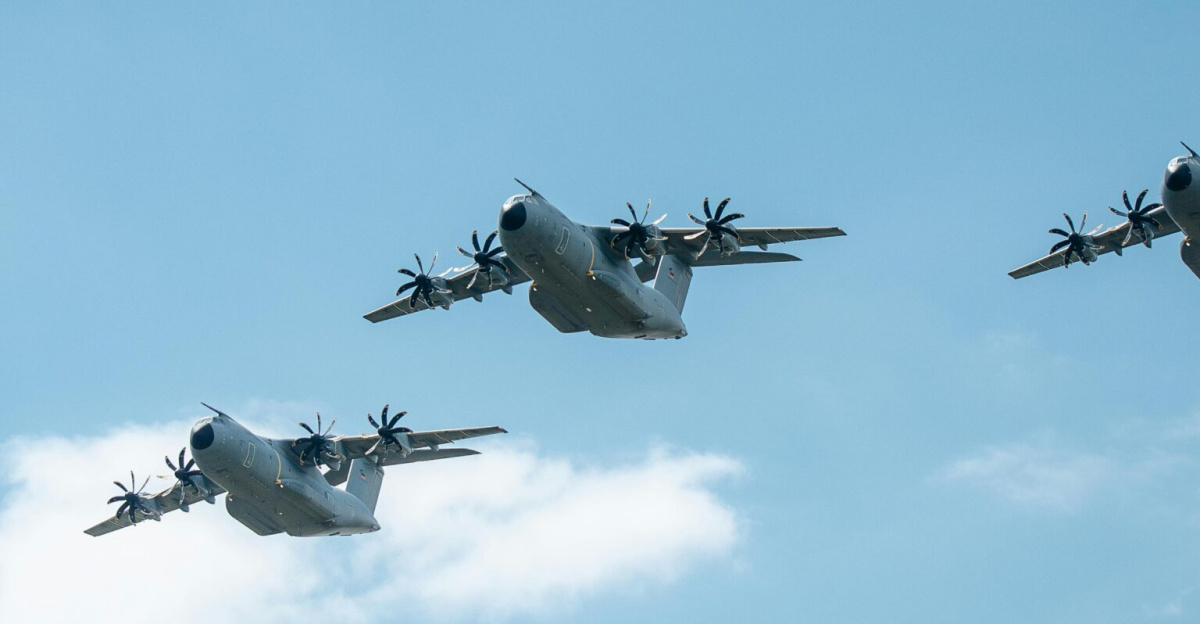 Three military aircraft flying in formation against a blue sky with clouds, showcasing power and precision.