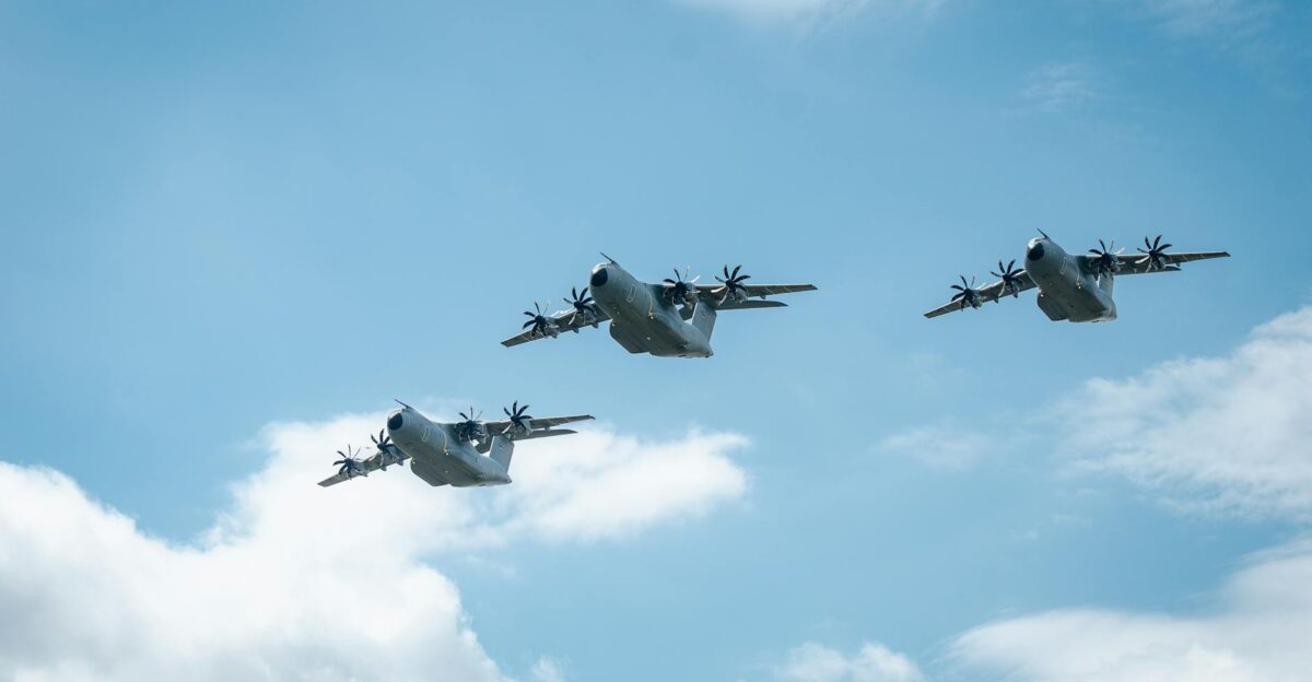 Three military aircraft flying in formation against a blue sky with clouds showcasing power and precision