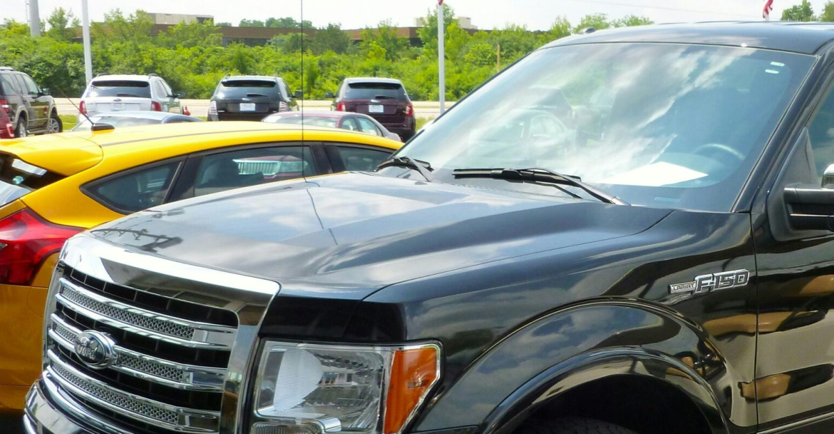 Black Ford F-150 pickup truck displayed at an outdoor dealership lot on a sunny day.