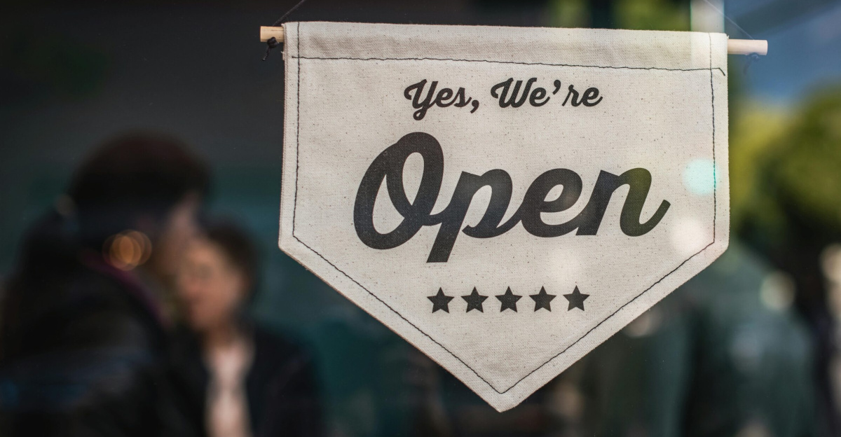 Welcoming open sign displayed in a shop window with blurred background.