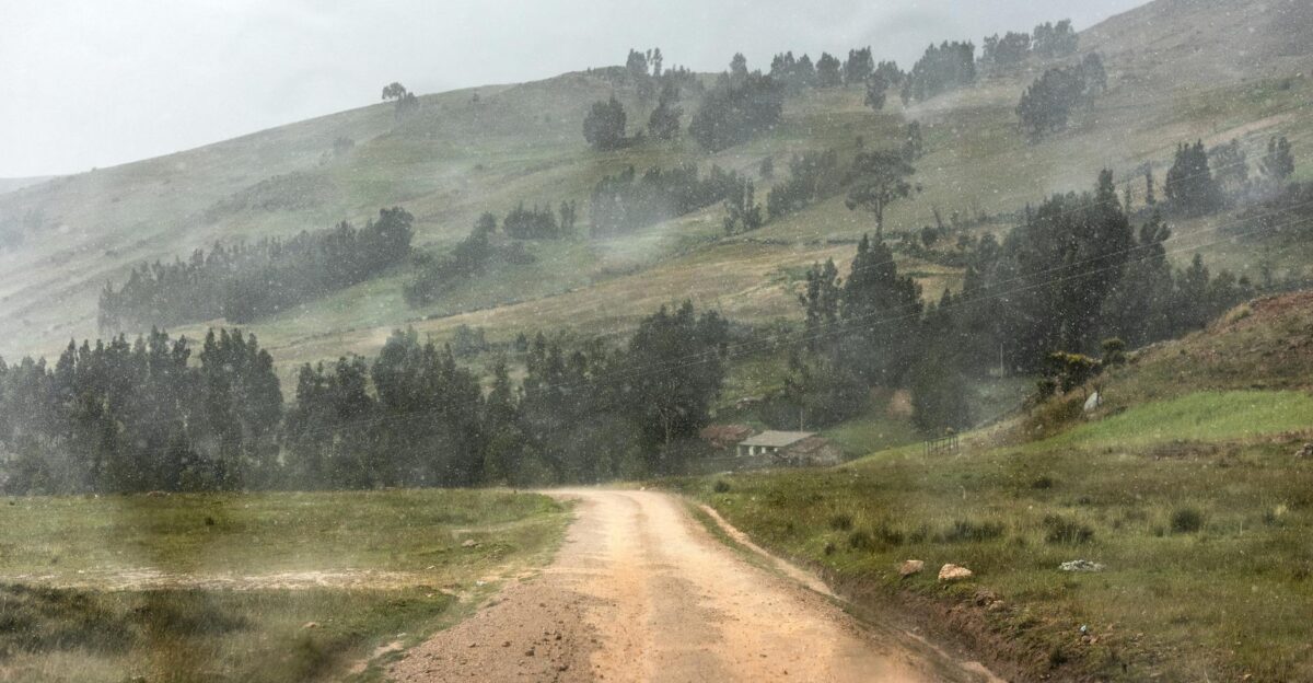 Dirt road cutting through a rainy mountainous landscape in rural Peru