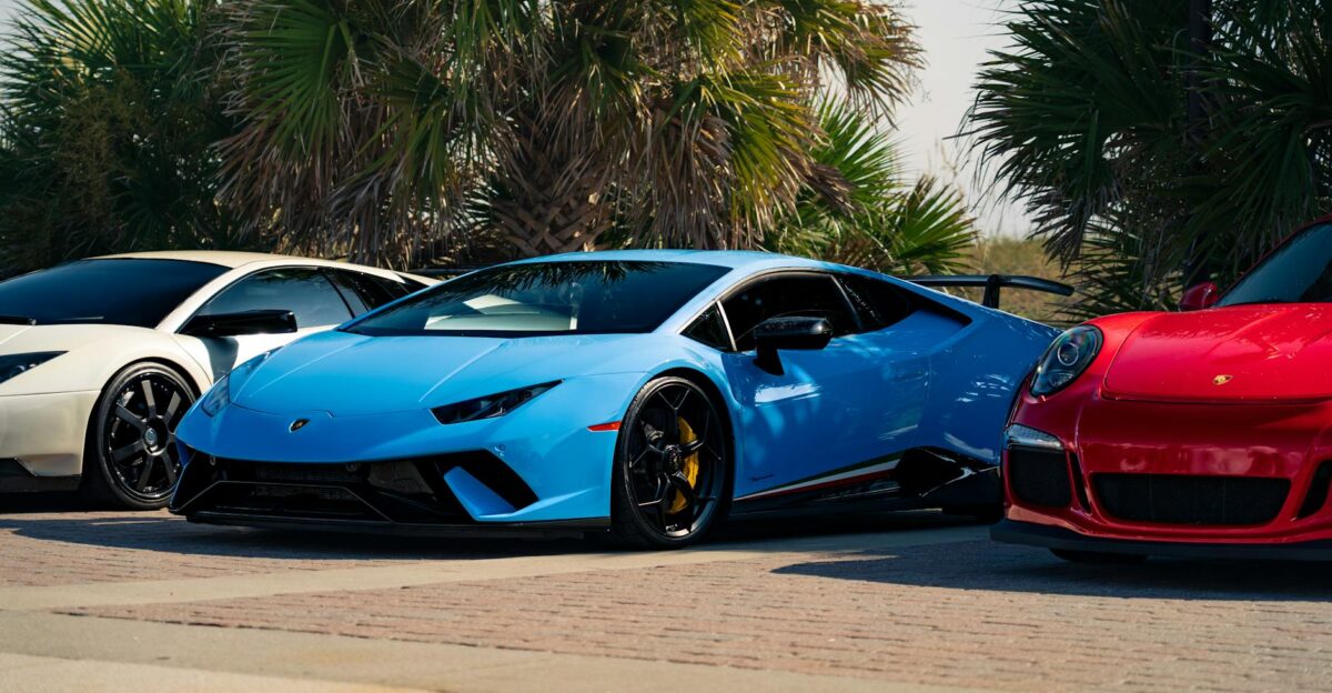 High-end sports cars parked among palm trees showcasing sleek design and vibrant colors