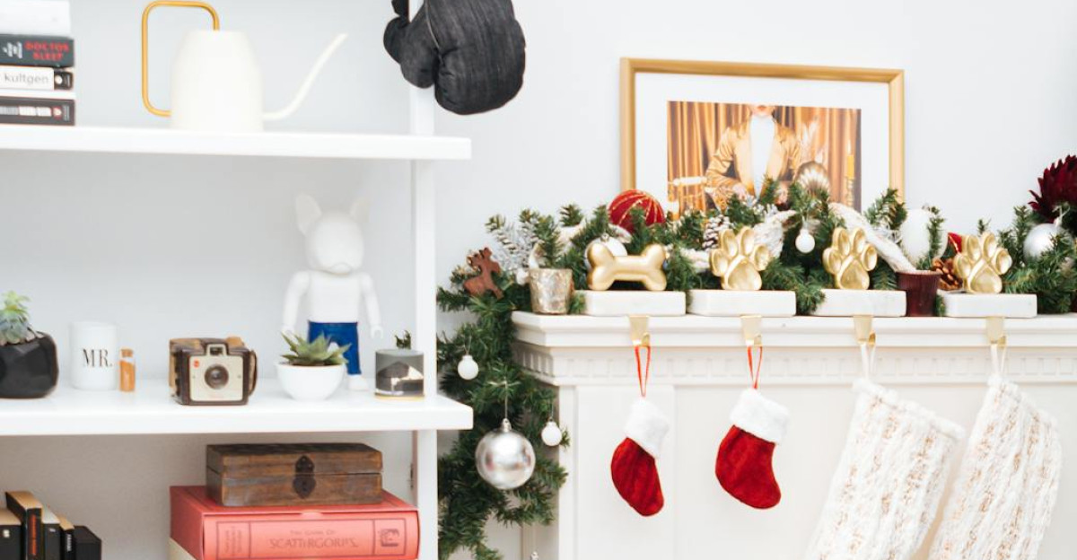 White shelf and fireplace decorated for Christmas featuring stockings and greenery