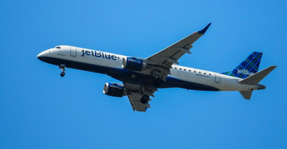 JetBlue airplane flying in clear blue skies, showcasing aviation in motion.