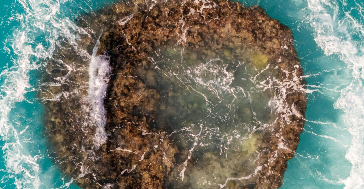 A stunning aerial view of a rocky island surrounded by turquoise waters and breaking waves in Bermuda.