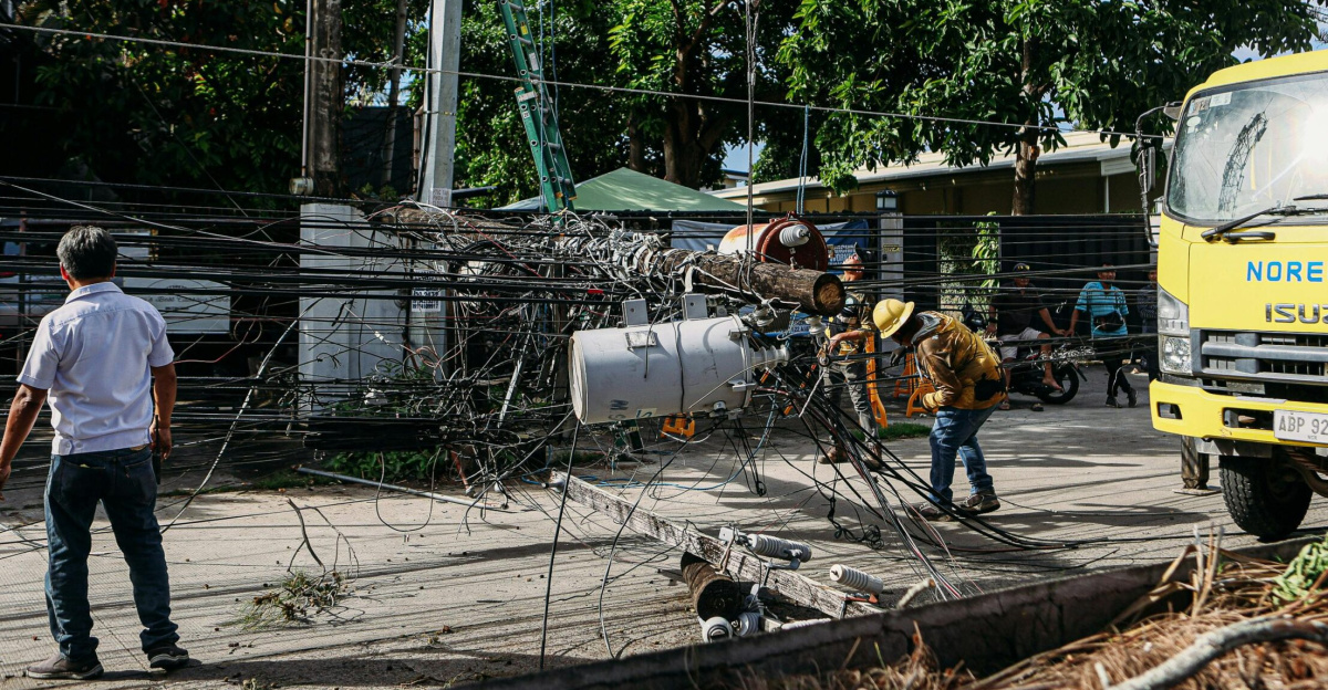 Team of workers in hard hats repairing electrical lines from a fallen pole after an accident.