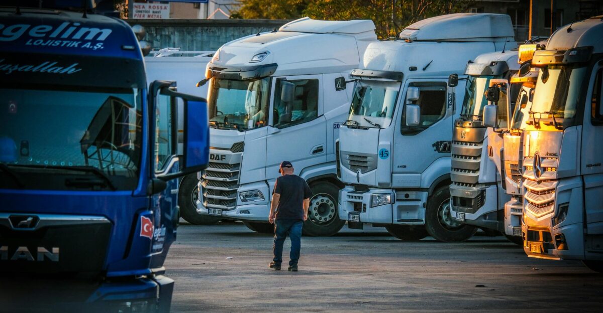 A man walks among parked trucks at sunset in an industrial area creating a serene yet busy scene