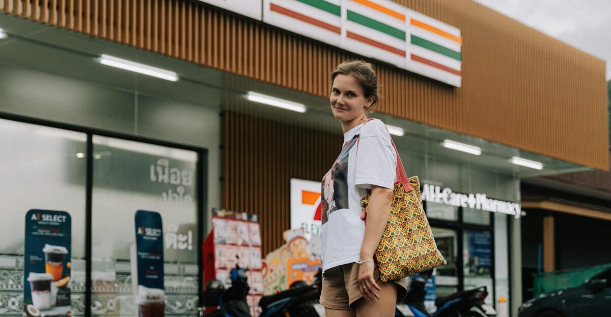 A woman standing in front of a 7-Eleven store in Phuket Thailand with a casual pose