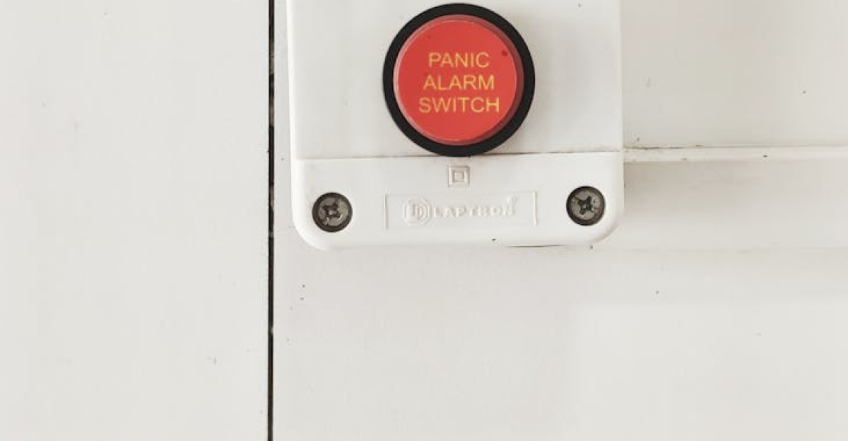 A red panic alarm switch mounted on a clean white wall emphasizing safety measures indoors