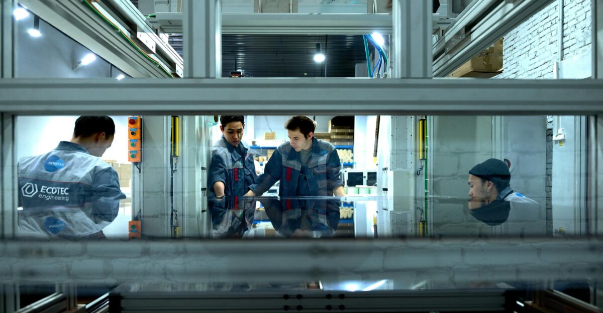 Engineers collaborate over advanced machinery in a high-tech indoor workspace