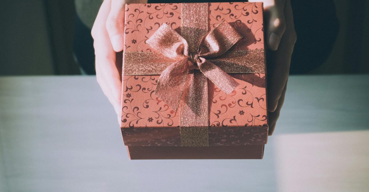 Hands presenting a beautifully wrapped gift box with a floral pattern perfect for any celebration