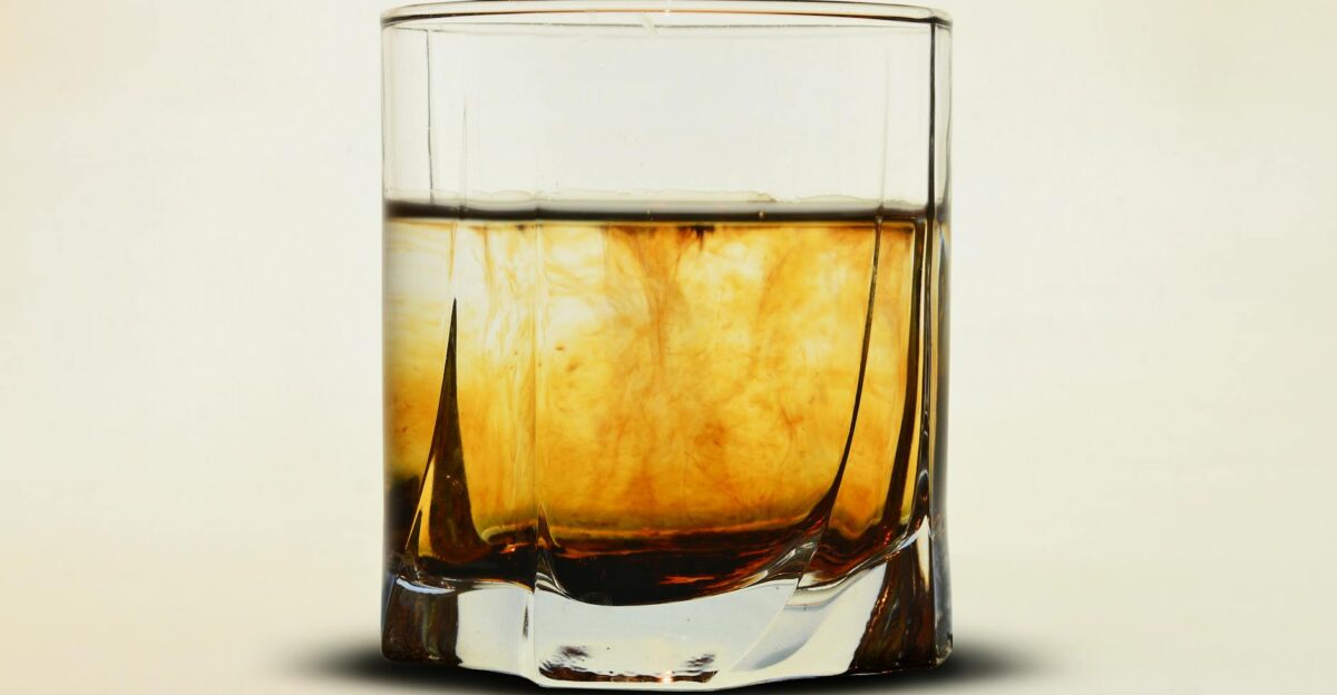 Close-up of an amber whiskey in a glass with a soft neutral backdrop perfect for beverage themes