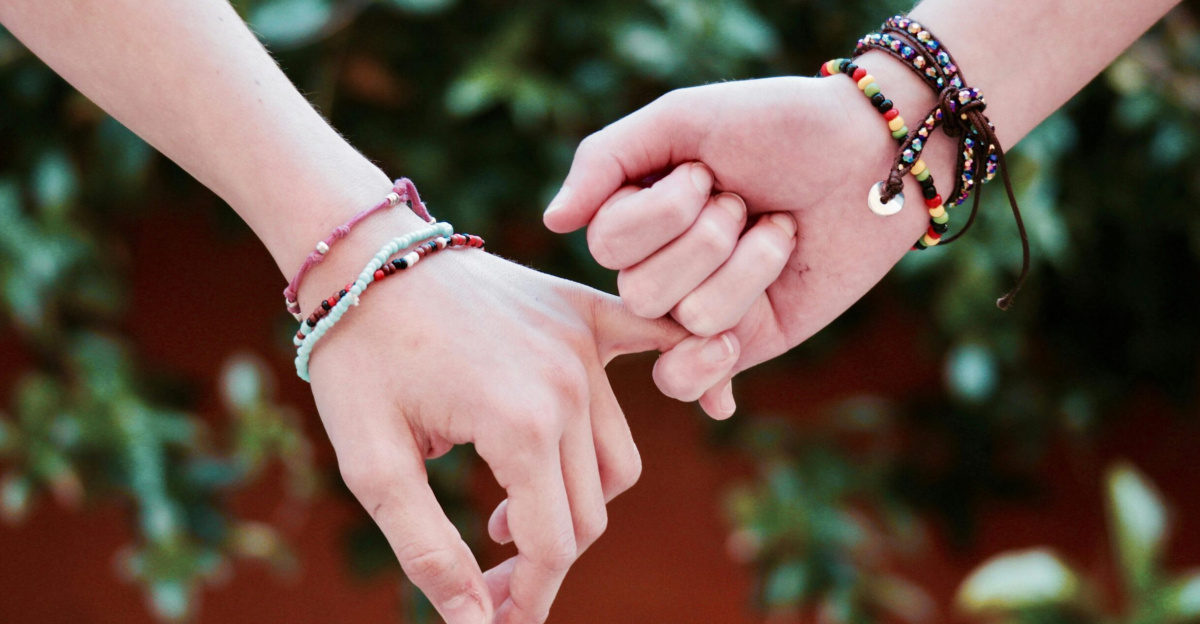 Two hands with colorful bracelets interlocked, symbolizing friendship and connection.