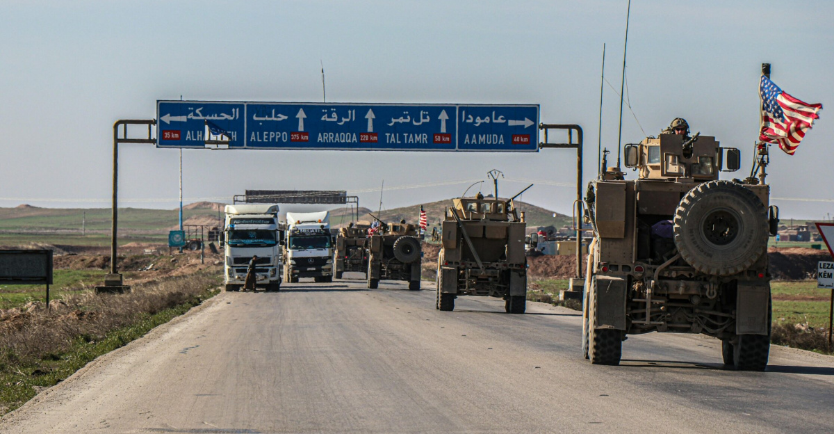 US military convoy travels on a highway in Al Hasakah, Syria, under blue skies.