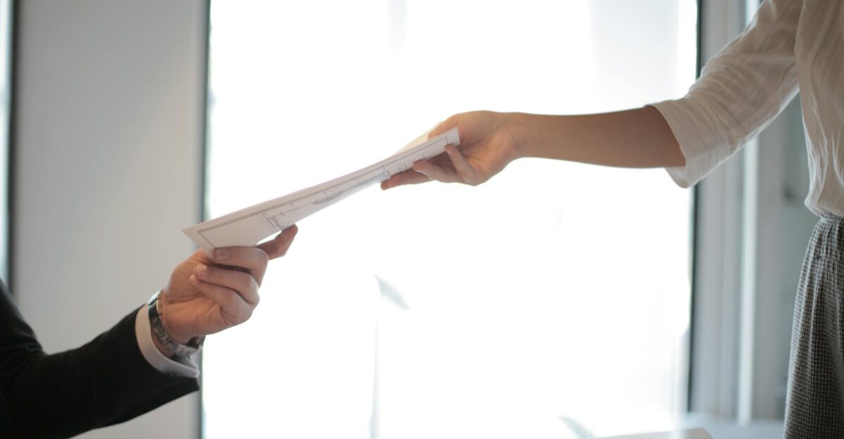 Close-up of hands exchanging documents in a business setting indoors