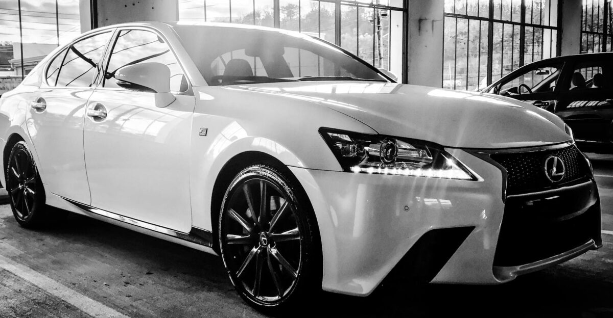 A stylish Lexus sedan showcased in a black and white indoor setting highlighting its luxury design